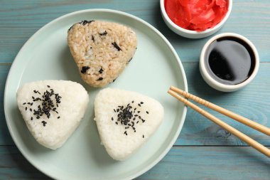 Pirinç topları (onigiri) açık mavi ahşap masa üzerinde servis edilir. Geleneksel Japon yemeği