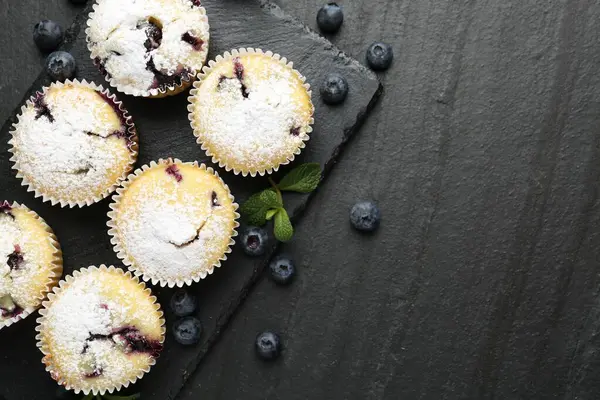 Yaban mersinli lezzetli çörekler, pudra şekeri ve siyah desenli masada nane şekeri, düz yatak. Metin için boşluk