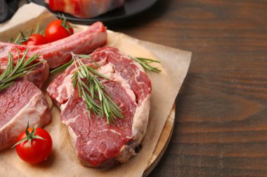 Çiğ sığır eti, biberiye ve domatesler ahşap masada, yakın plan. Metin için boşluk