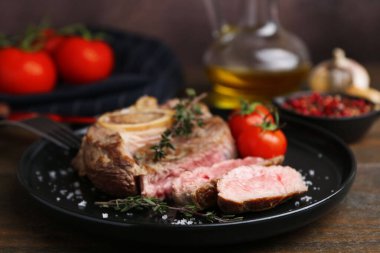 Lezzetli et parçaları, ahşap masada baharatlar ve domatesler, yakın plan.