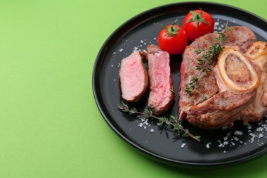 Lezzetli et parçaları, kekik, yeşil arka planda tuz ve domates, yakın plan. Metin için boşluk