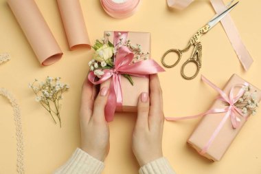 Çiçek kutuları, çiçekler, makas ve bej arka planda kurdele olan çiçekçi.