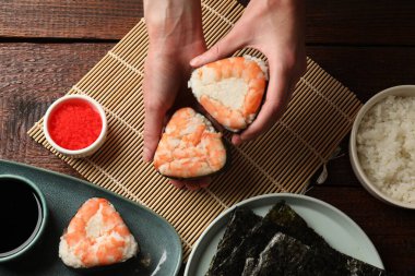 Lezzetli onigiri (Japon pirinç topları) taşıyan kadın ahşap masada karides, üst manzara