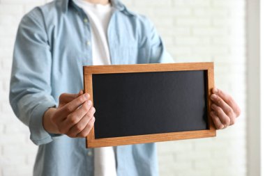 Kapalı alanda boş küçük tahta tutan adam, yakın plan.