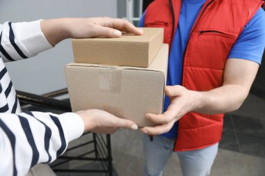 Kurye içerideki alıcıya paketler veriyor, yakın plan.