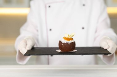 Mutfaktaki beyaz ahşap masada lezzetli bir tatlıyla şekerlemeci, yakın plan.