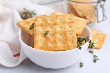 Lezzetli tuzlu krakerler ve kekik beyaz masada, yakın plan.