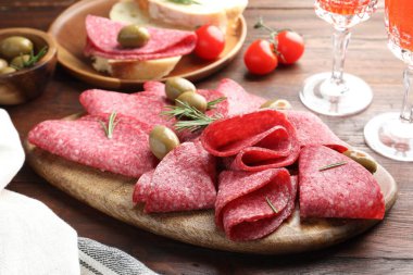 Ahşap masada servis edilen zeytinli ve biberiyeli lezzetli sosisler.