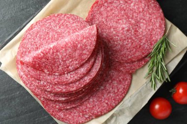 Lezzetli füme sosis, biberiye ve domatesler siyah masada, düz yerde.