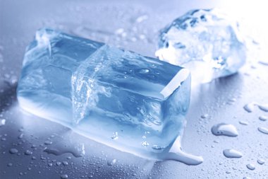 Temiz buz parçaları ve su açık mavi masaya düşer.