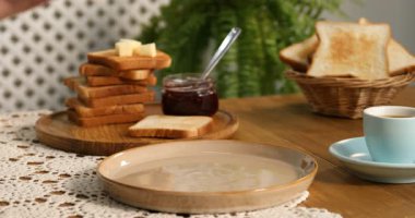 Ahşap masada tereyağı ve reçelli tost yiyen kadın, yakın plan.