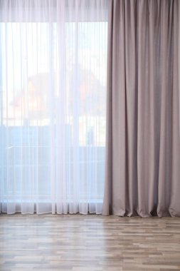 Boş odada zarif perdeleri olan pencere.