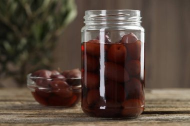 Cam kavanozda zeytin turşusu ve ahşap masada kase, yakın plan.