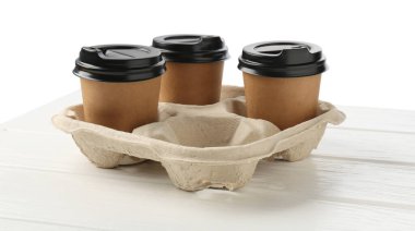 Kağıt kahve bardakları beyaz ahşap masadaki karton tutacakta, yakın plan.