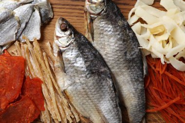 Ahşap masada birçok farklı kurutulmuş balık atıştırması, yakın plan.