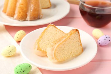 Lezzetli kek parçaları, pembe ahşap masada paskalya yumurtası ve çay, yakın plan.