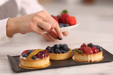 Şekerci tartı yaban mersiniyle süslüyor, yakın plan.