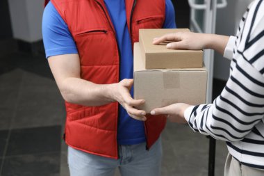 Kurye içerideki alıcıya paketler veriyor, yakın plan.