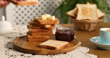 Ahşap masada tereyağı ve reçelli tost yiyen kadın, yakın plan.