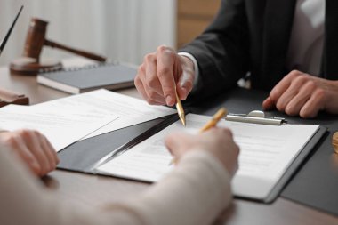 Belgeye işaret eden noter ve müşterinin masa içine imza koyması, yakın plan