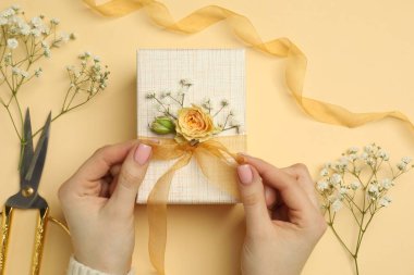 Çiçek kutusu, çiçek, makas ve bej arka planda kurdele olan bir çiçekçi.