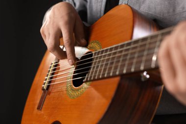 Siyah arkaplanda gitar çalan adam, yakın plan
