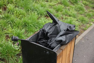 Dışarıdaki çöp kutusunda kırık siyah şemsiye.