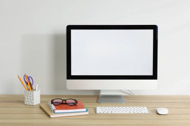 Bilgisayar, klavye, fare, farklı kırtasiye malzemesi ve beyaz arkaplana karşı ahşap ofis masasında gözlük