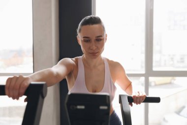 Spor salonunda spor bisikleti eğitimi alan atletik kadın.