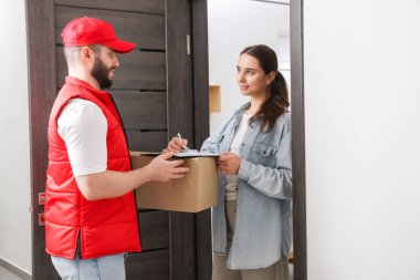 Kutulu ve alıcısı olan kurye paket teslimatı için içeride imza atıyor.