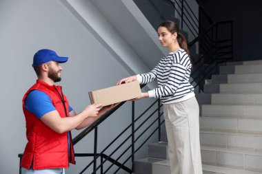 Gülen kurye içerideki alıcıya paket veriyor.