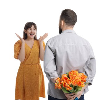 Adam beyaz arka planda sevgili karısına güzel laleler saklıyor.