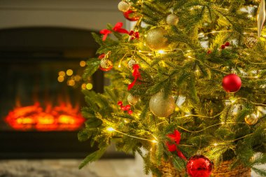 Evdeki şöminenin yanında güzel dekore edilmiş Noel ağacı, yakın çekim. Bokeh etkisi