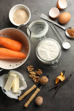 Koyu dokulu masa üzerinde havuçlu kek ve mutfak malzemesi yapmak için farklı malzemeler.