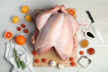 Whole raw turkey and ingredients on white wooden table, flat lay