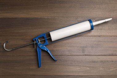 Ahşap arka planda bir tutkal tabancası, üst manzara. Yapı aracı