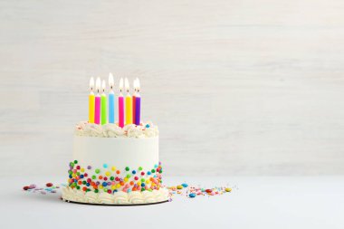 Renkli süslemeli nefis bento keki ve beyaz masada yanan mumlar. Metin için boşluk