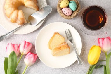 Lezzetli kek parçaları, Paskalya yumurtaları, laleler ve çay gri masada, düz yatıyordu.