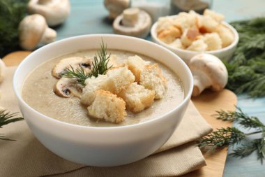 Ekmek arası mantar kremalı çorba, dereotu ve malzemeler mavi masada, yakın plan.