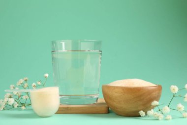Kolajen tozu, kase, kepçe, bir bardak su ve turkuaz arka planda çingene çiçeği.