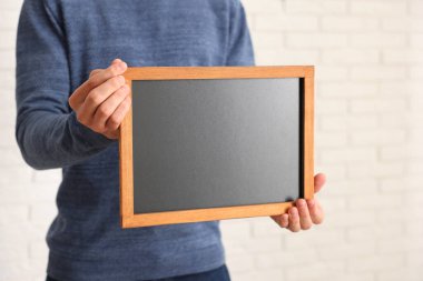 Kapalı alanda boş küçük tahta tutan adam, yakın plan.