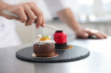 Şekerci mutfakta lezzetli bir tatlı hazırlıyor, seçici bir odak noktası.