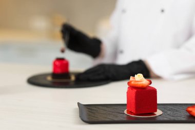 Mutfaktaki beyaz ahşap masada leziz bir tatlı süsleme, seçici bir odak noktası.