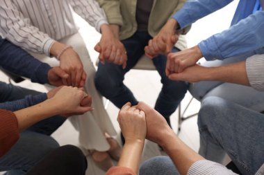 Grup psikoterapi seansı sırasında el ele tutuşan insanlar kapalı mekanda, yakın çekim