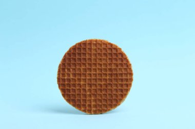Açık mavi arkaplanda lezzetli yuvarlak bir waffle.