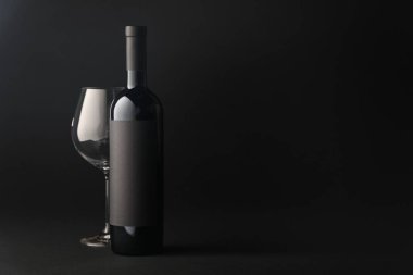 Siyah zemin üzerinde şarap ve cam şişesi, metin için boşluk