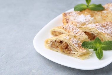 Pudra şekerli elmalı turtalar ve açık gri masada nane şekeri, yakın plan. Metin için boşluk