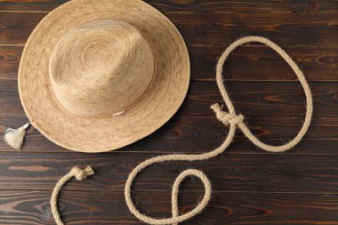 Pamuk ipten yapılmış kement ve ahşap arka planda hasır şapka, düz yatıyordu.