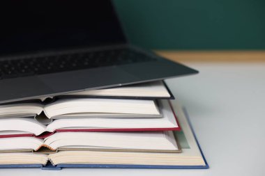 Masada yazı tahtasına karşı yığınla kitap ve dizüstü bilgisayar var.