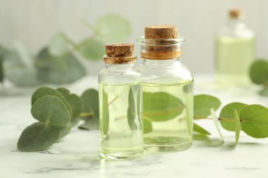 Gerekli yağ ve okaliptüs şişeleri beyaz mermer masa üzerinde, yakın çekim